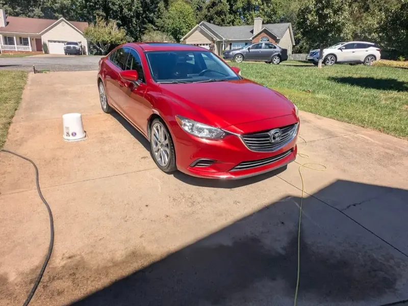 Red Mazda sedan washed in a driveway in Hickory