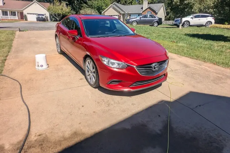 Red Mazda sedan washed in a driveway in Hickory